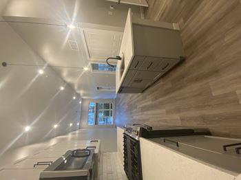 a modern kitchen with white countertops and a wood wall at The Yards at Malvern, Malvern, 19355